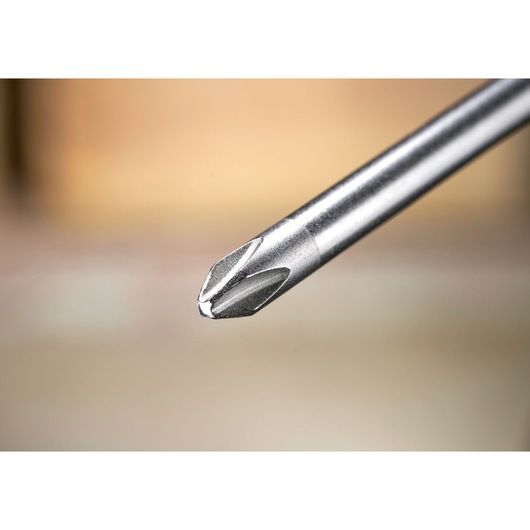 Close-up van een metalen kruiskopschroevendraaierpunt met een wazige achtergrond.