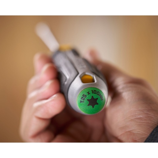 Hand houdt een STANLEY T25 x 100mm schroevendraaier met groene uiteinde en ergonomische grip.