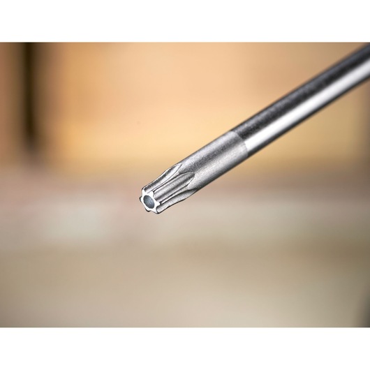 Close-up van een metalen precisieschroevendraaierbit met sterpunt, tegen een vage achtergrond.
