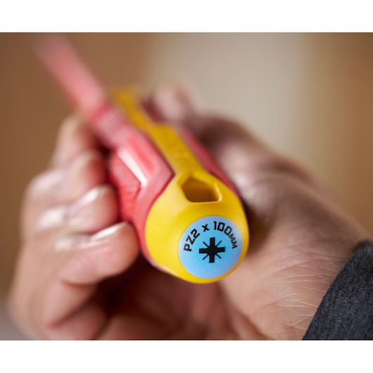 Gros plan sur une main tenant un tournevis STANLEY, marquage PZ2 x 100mm sur la poignée jaune.