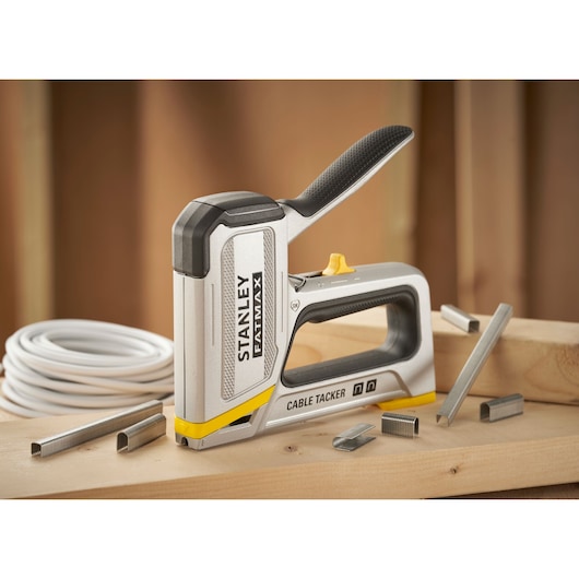 Outil cable tacker STANLEY FMHT70100-0 sur surface en bois avec agrafes et câble visibles.