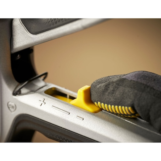STANLEY FMHT70100-0 agrafeuse en gros plan, gant ajustant le curseur jaune de réglage de pression.