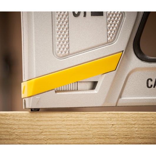 STANLEY FMHT70100-0 photographie du coin d'une agrafeuse, détail argenté et jaune sur surface en bois.