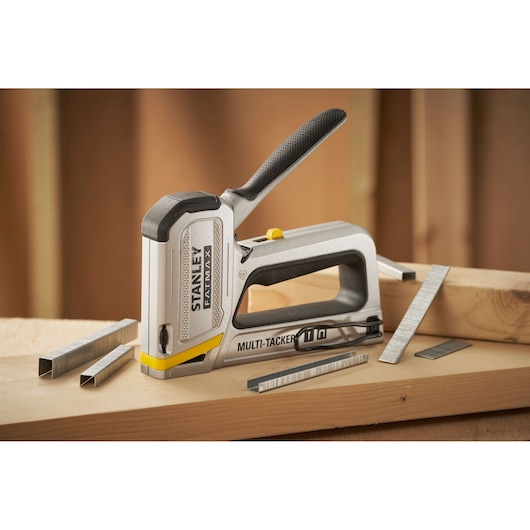 Stanley FMHT70250-0 agrafeuse avec agrafes sur une surface en bois, FATMAX Multi-Tacker poignée ergonomique.