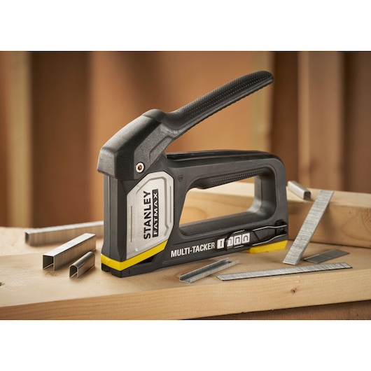 Outil STANLEY FMHT70401-0 multi-tacker avec agrafes sur surface en bois, vue latérale.