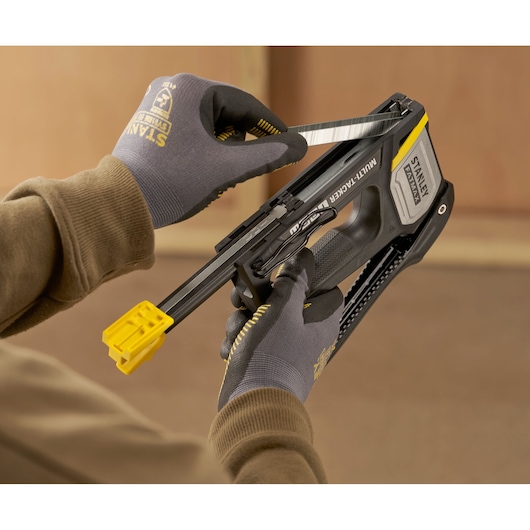Photo de l’agrafeuse STANLEY FMHT70401-0 chargée de agrafes, tenue en main avec des gants.