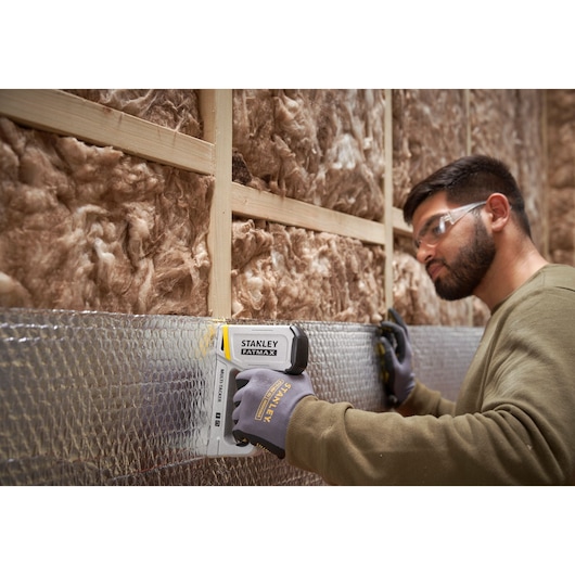 Agrafeuse STANLEY FMHT70443-0 en utilisation, fixant un isolant sur une ossature en bois.