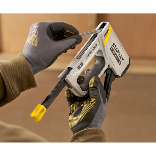 Photo de STANLEY FMHT70443-0 multi-tacker chargé d’agrafes, tenu par des mains gantées lors de l’utilisation.