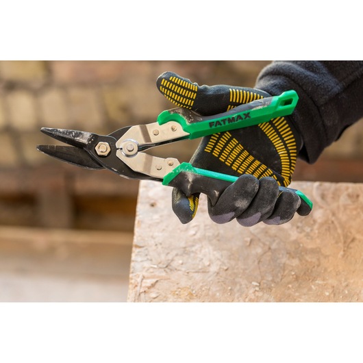 STANLEY FMHT73557-0 luchtknipschaar met groene handgreep vastgehouden in een gehandschoende hand, close-up.