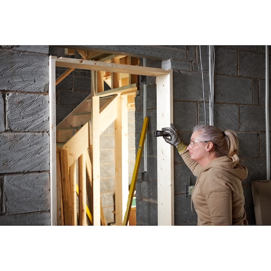 STANLEY FMHT77165-0 télémètre laser utilisé sur un cadre de porte en bois sur chantier.