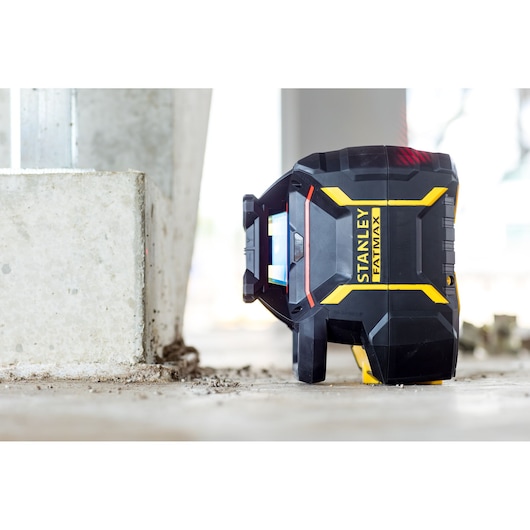 STANLEY FMHT77446-1 niveau laser noir et jaune sur sol de chantier, vue latérale.