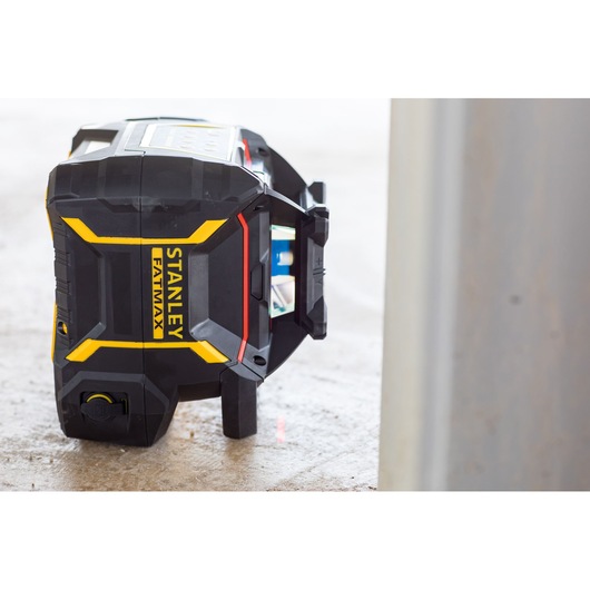 STANLEY FMHT77447-1 appareil niveau laser, noir avec accents jaunes, vue latérale, sur sol de chantier.