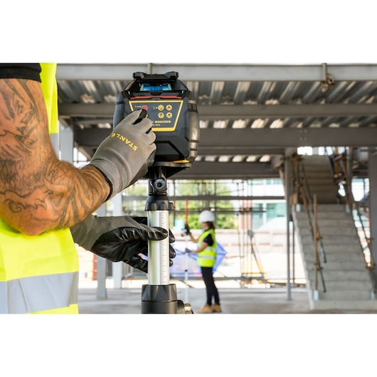 Niveau laser rotatif STANLEY FMHT77449-1 sur trépied, utilisé sur un chantier de construction.
