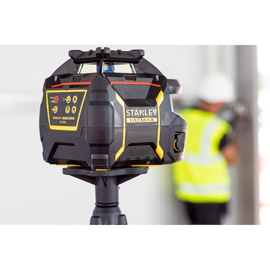 STANLEY FMHT77449-1 niveau laser rotatif sur trépied, noir et jaune, environnement chantier.