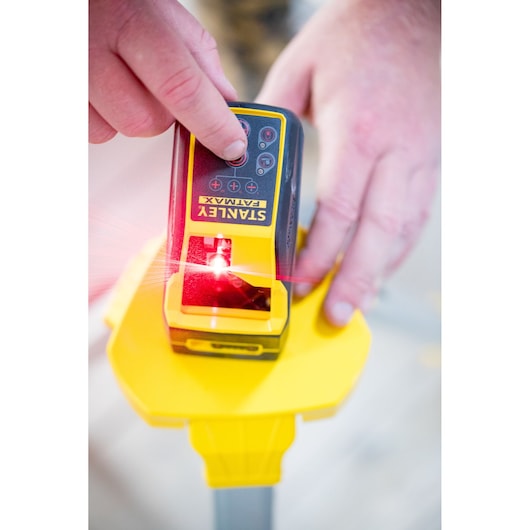 Foto van STANLEY FMHT77585-1 laserwaterpas in gebruik, met rode laser, op gele statiefvoet.