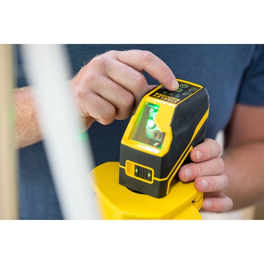 Foto van STANLEY FMHT77586-1 laserwaterpas in gebruik, geel en zwart handgereedschap met digitale bediening.