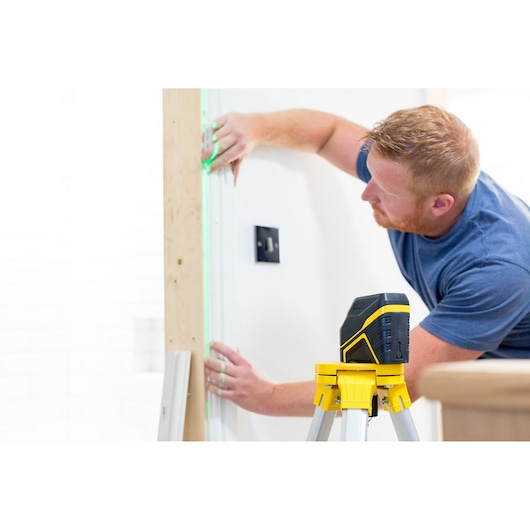 STANLEY FMHT77595-1 laserwaterpas op statief, groene lijn geprojecteerd op muur tijdens installatie.