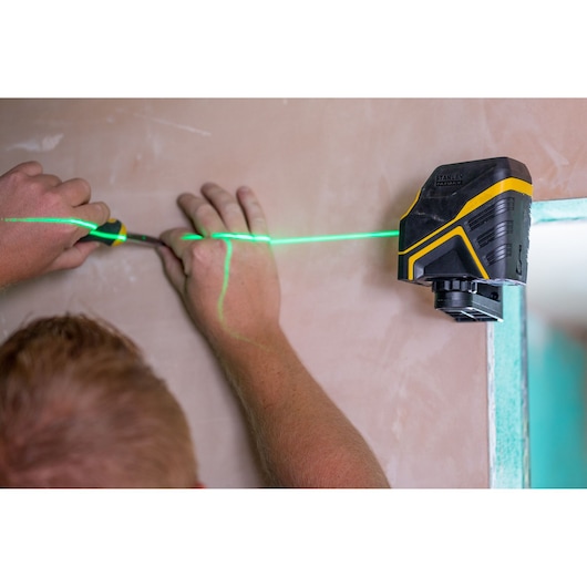 STANLEY FMHT77595-1 laserwaterpas projecteert groene lijn op muur voor uitlijning tijdens installatie.