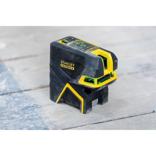 STANLEY FMHT77598-1 laserwaterpas, zwart en geel, fotografie van gereedschap op houten oppervlak.