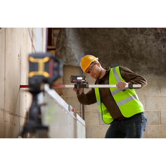 Niveau laser STANLEY FMHT77652-0 utilisé sur chantier par ouvrier en gilet haute visibilité.