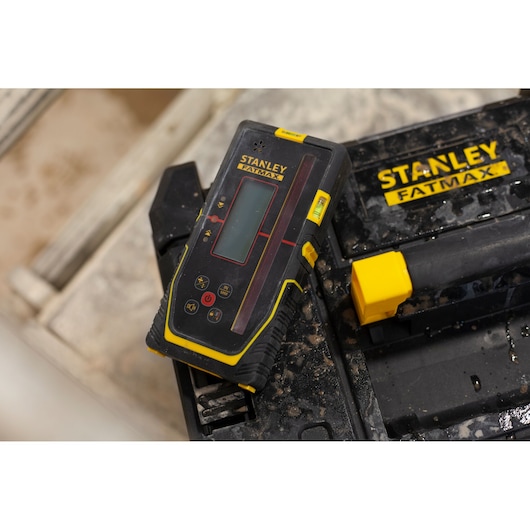 STANLEY FMHT77652-0 niveau laser avec accents jaunes posé sur une boîte à outils STANLEY FATMAX, vue rapprochée.