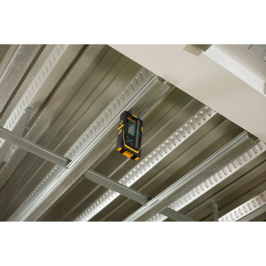 Foto van STANLEY FMHT77653-0 laserdetector bevestigd aan metalen plafondframe, voorkant display zichtbaar.
