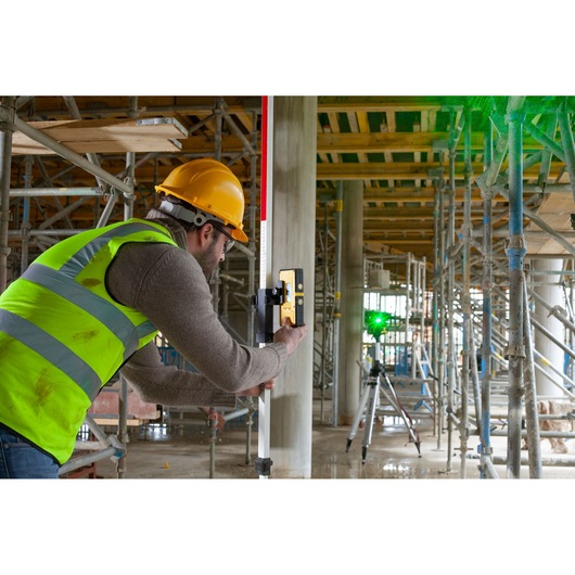 STANLEY FMHT77653-0 laserontvanger gebruikt op bouwplaats met steigers en medewerker in veiligheidskleding.