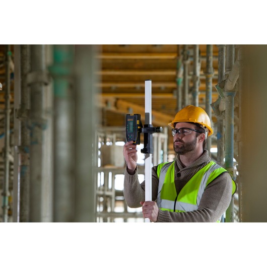 STANLEY FMHT77653-0 laserdetector op staaf vastgehouden door werker met hesje en helm op bouwplaats