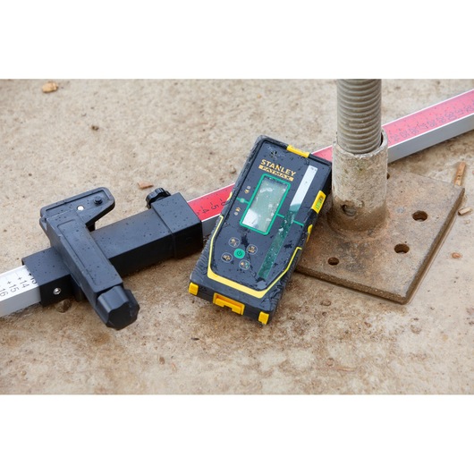 Stanley FMHT77653-0 laserontvanger op bouwplaats met waterpaslat en grondplaat.