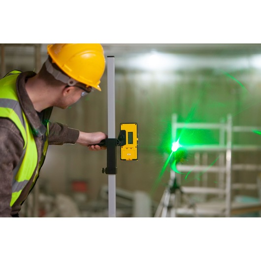 STANLEY FMHT77653-0 laserdetector vastgehouden door werknemer bij groene laserstraal, bouwlocatie.