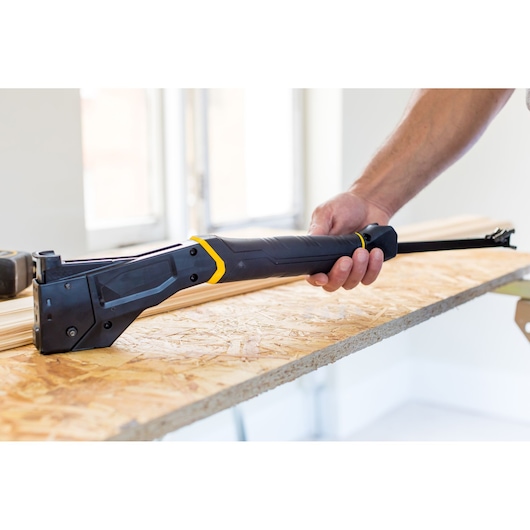 STANLEY FMHT81394-9 scie à main noir et jaune, tenue sur une planche en bois dans un environnement de chantier.