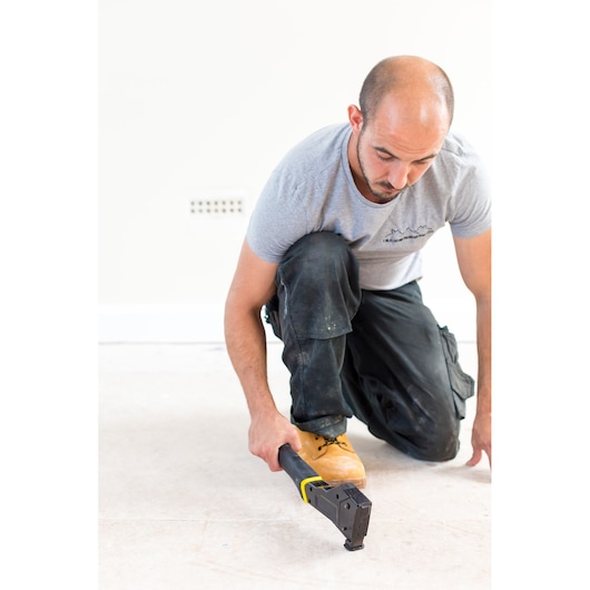 STANLEY FMHT81394-9 agrafeuse manuelle pour sol en utilisation, personne agenouillée sur le sol brut.