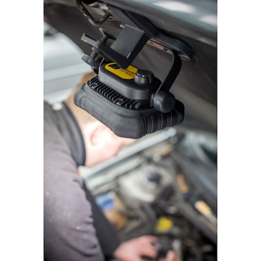 Lampe de travail STANLEY FMHT81507-1 fixée sous le capot d'une voiture, éclairant le moteur pendant une réparation.