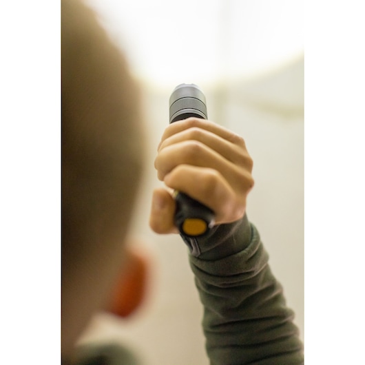Foto van een persoon met een STANLEY FMHT81511-0 zaklamp, focus op de hand die het handvat vasthoudt.