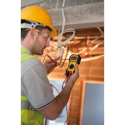 STANLEY FMHT82563-0 digitale multimeter gebruikt door een werknemer op een bouwplaats om elektrische draden te testen.