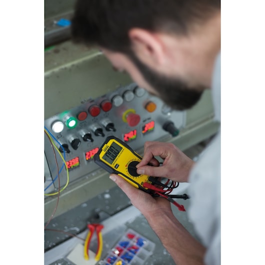 Foto van STANLEY FMHT82565-0 digitale multimeter die gebruikt wordt bij een bedieningspaneel; geel-zwart apparaat.
