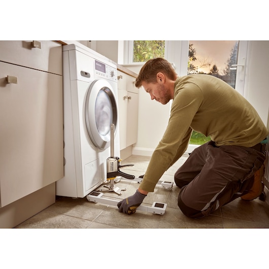 STANLEY FMHT83550-1 handgereedschap gebruikt om wasmachine op te tillen tijdens keukeninstallatie.
