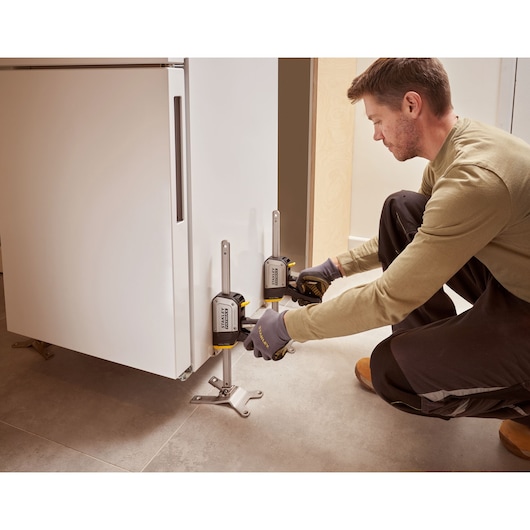 Foto van STANLEY FMHT83550-1 kasthefapparaat dat een witte kast tilt bij installatie.