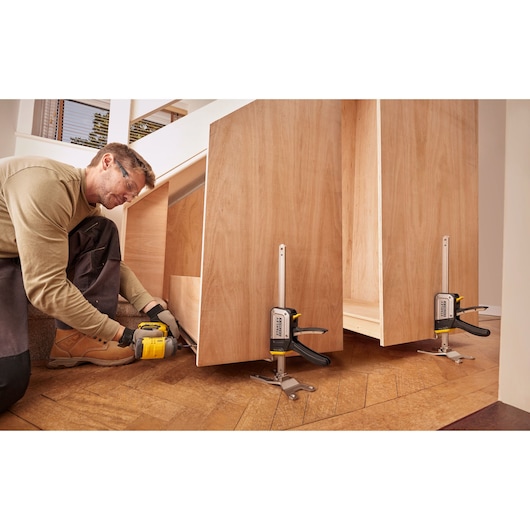 STANLEY FMHT83550-1 steun-klem houdt houten panelen vast tijdens montage op houten vloer.