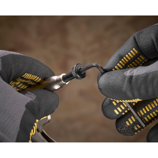 Mains gantées ajustent une vis sur un outil Stanley à l'aide d'une clé Allen.