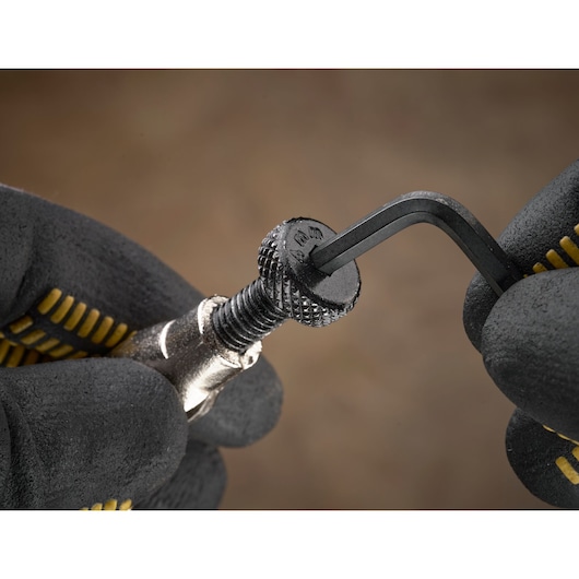 Mains gantées utilisant une clé Allen pour ajuster une vis moletée, vue rapprochée de l'action.