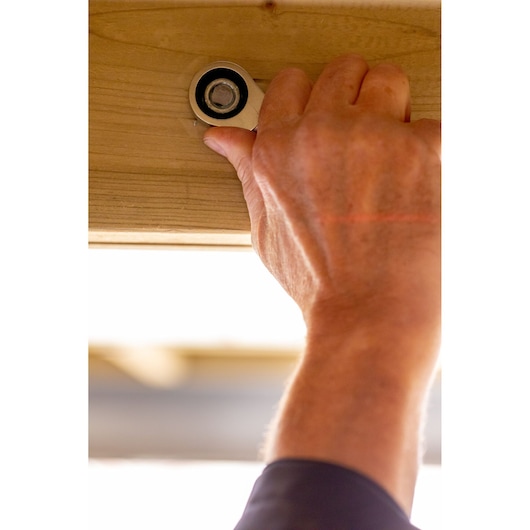 Clé à cliquet STANLEY FMMT13109-0 serrant un boulon sur une poutre en bois, gros plan, produit en utilisation.