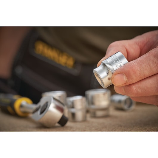 STANLEY FMMT17216-0 dopsleutelset, hand houdt zilveren dop, ratel en doppen zichtbaar.