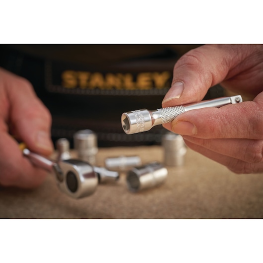 Photo de STANLEY FMMT25125-0 clé à douille et accessoire tenu en main, autres douilles à proximité.