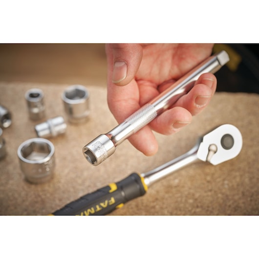 STANLEY FMMT25131-0 dopsleutel verlengstuk in hand, met chromen doppen en ratel op werkbank.