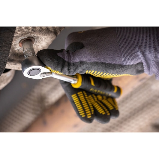 STANLEY FMMT82683-0 ratelsleutel in gebruik, gehandschoende hand draait metalen bout, close-up.