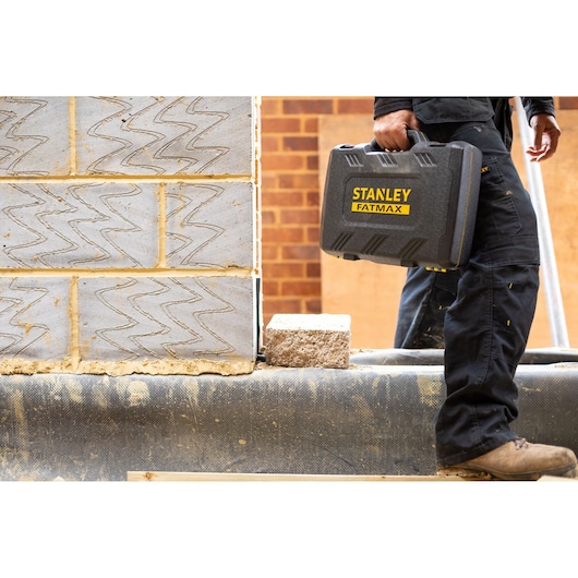 Stanley FMMT82684-1 FATMAX harde gereedschapskoffer gedragen door werknemer op bouwplaats.