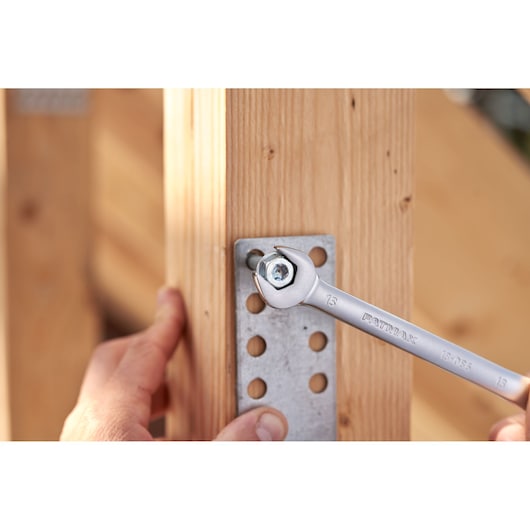 Photo de la clé à cliquet STANLEY FATMAX FMMT82848-0 serrant un boulon sur une équerre métallique fixée au bois.