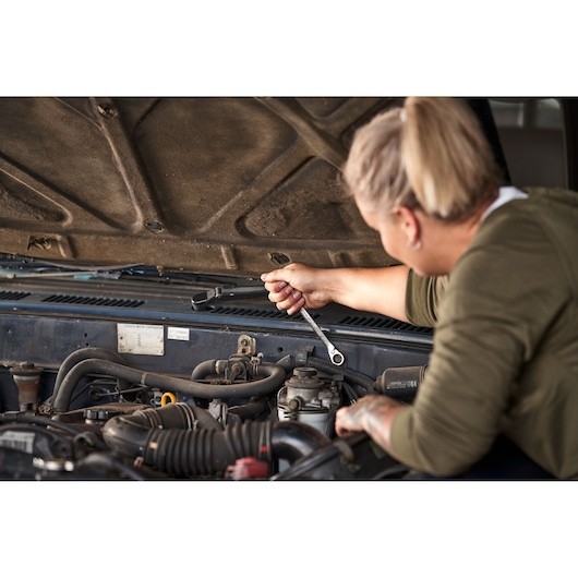 Personne utilisant la clé à cliquet réversible STANLEY FATMAX sur moteur, STANLEY FMMT82848-0, outil pour réparation auto.