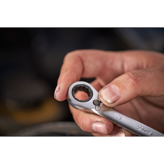Gros plan d'une main tenant la clé à cliquet réversible STANLEY FATMAX FMMT82848-0, vue sur le mécanisme.